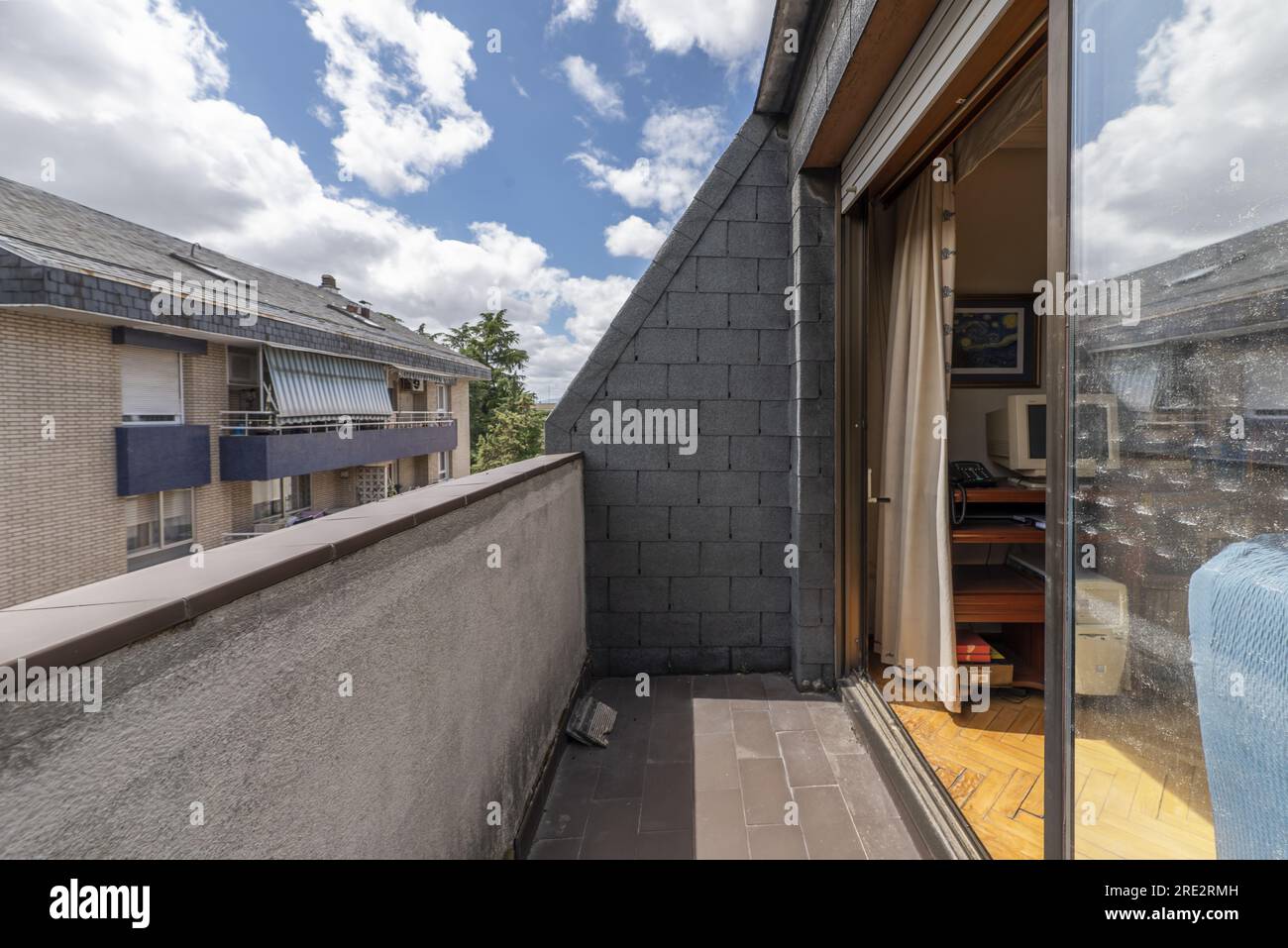 Apartment mit möbliertem Wohnzimmer und Zugang zu einer kleinen Terrasse in einem Gebäude mit schrägen Decken, Aluminium- und Glasverkleidungen Stockfoto