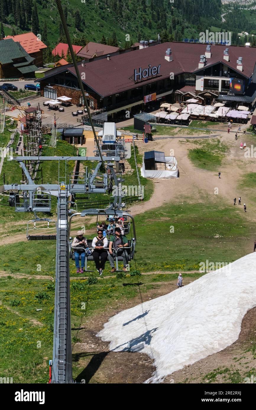 Kasachstan, Skigebiet Shymbulak. Touristen fahren im Sessellift. Stockfoto