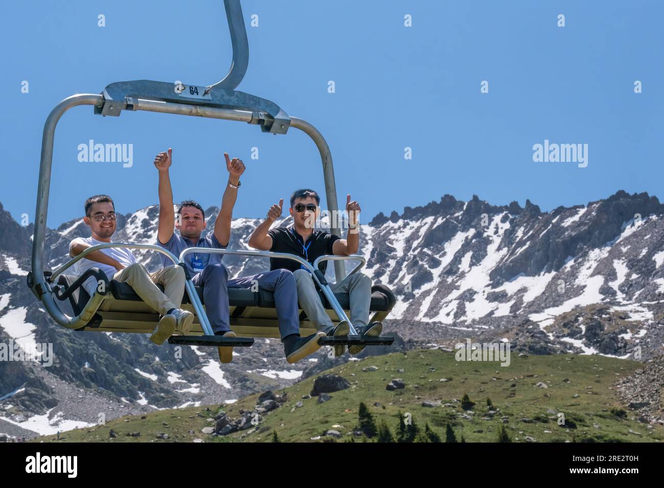 Kasachstan, Skigebiet Shymbulak. Touristen fahren im Sessellift. Stockfoto