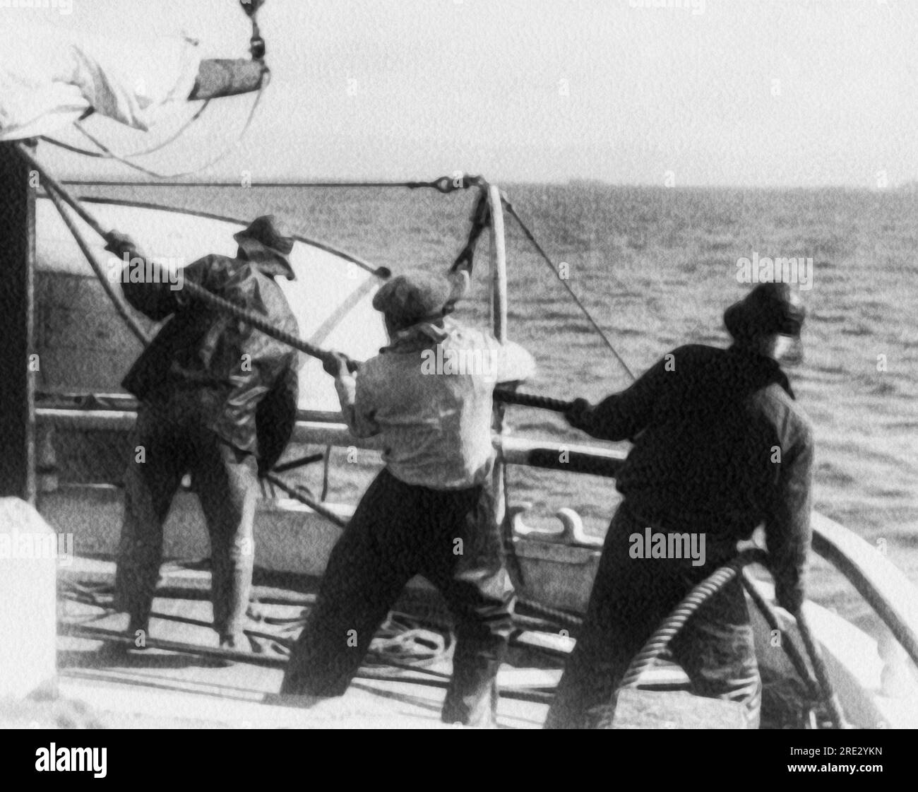 Welt: c. 1930 drei Matrosen auf einem Segelschiff, die an einem Seil ziehen. Stockfoto