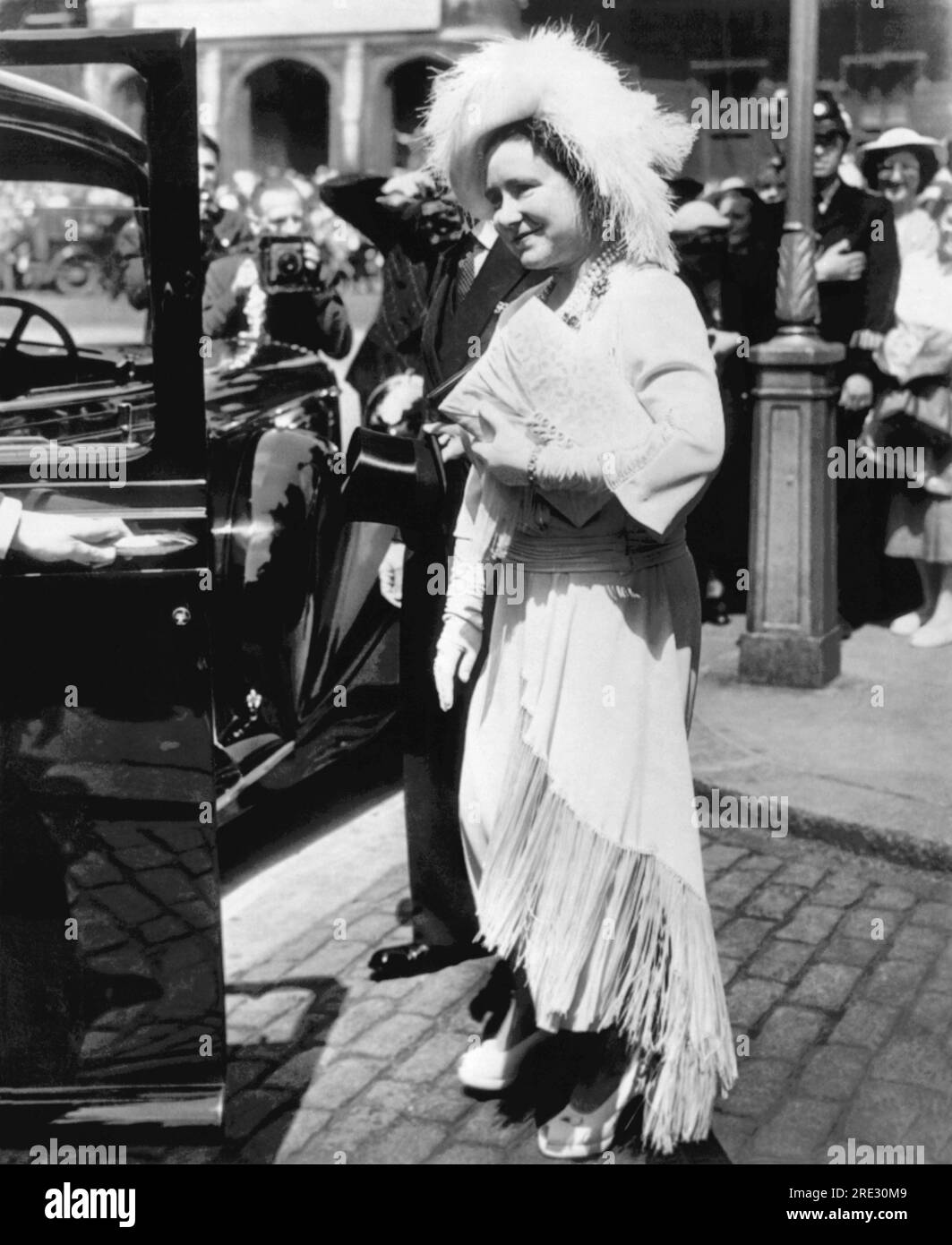 London, England: 29. Juli 1950 Queen Elizabeth verlässt eine Gedenkfeier in Westminster Abbey für städtische Polizisten, die in den beiden Weltkriegen getötet wurden. Sie trägt einen Straußenhut, eine Perlenkette, ein Kleid mit Seidenrand und Plateau-Schuhe. Stockfoto