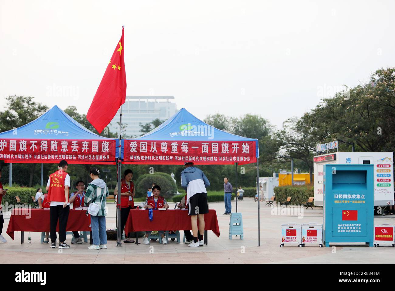 LIANYUNGANG, CHINA - 24. JULI 2023 - das Freiwilligendienst-Team stellt den Menschen vor Ort die relevanten Kenntnisse des nationalen Flaggengesetzes vor, Stockfoto