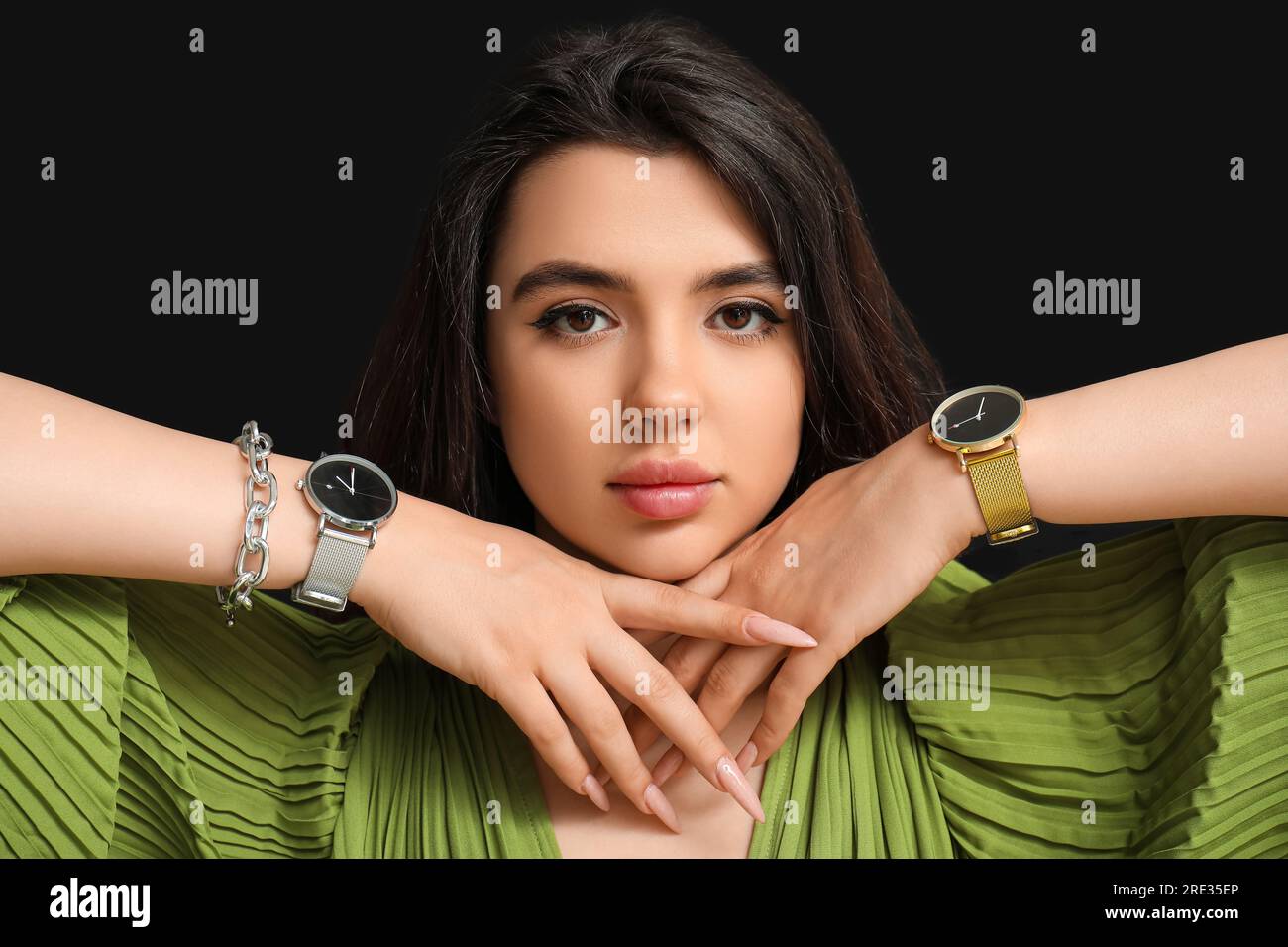 Wunderschöne junge Frau mit Armbanduhren auf schwarzem Hintergrund Stockfoto
