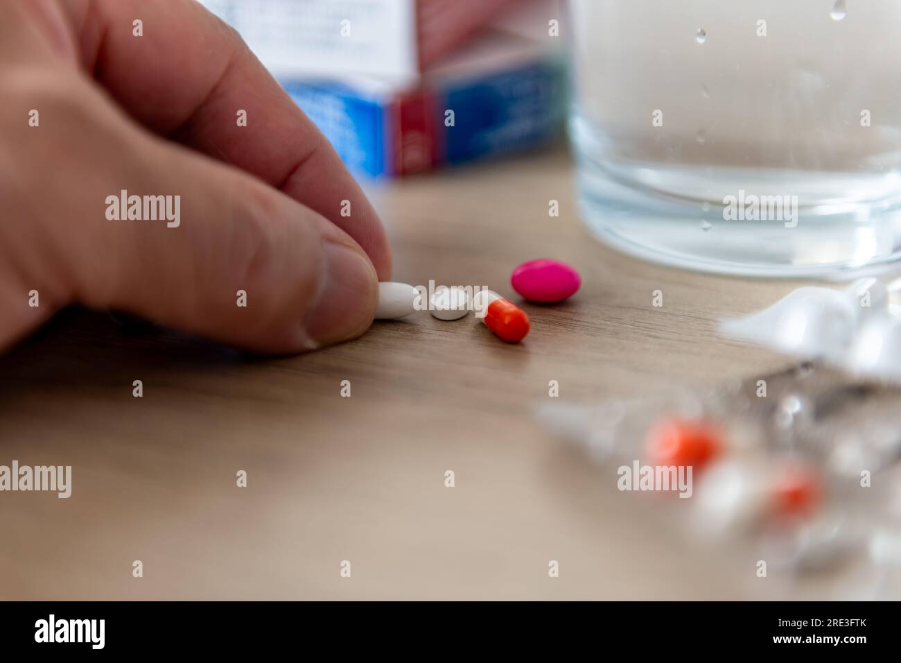 Eine Person, die verschreibungspflichtige Medikamente einnimmt, nimmt eine Tablette auf einer Arbeitsplatte ab. Stockfoto