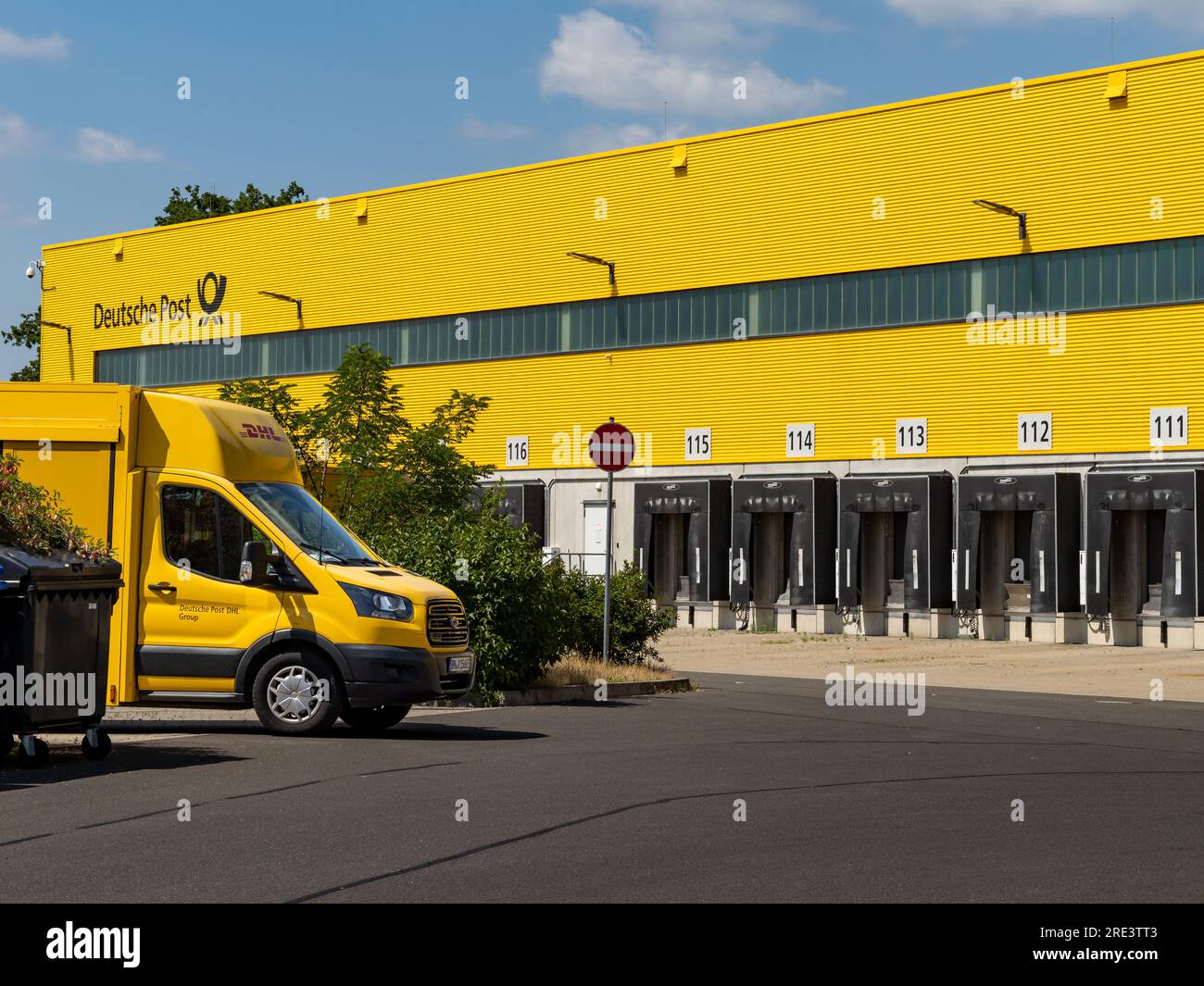 DHL-Auslieferungszentrum (MechZB) mit einem Lieferfahrzeug vor dem Hotel. Die Ladezonen sind leer. Das gelbe Industriegebäude stammt von der Deutschen Post Stockfoto