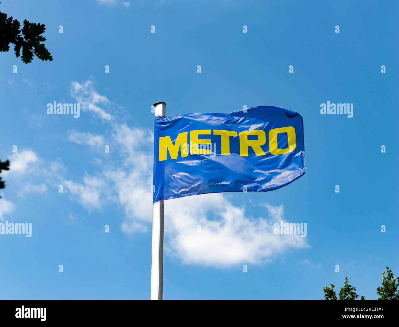 Logo des Großhändlers Metro auf einer Flagge hoch oben in der Luft. Der Cash and Carry Store bietet Geschäftsmitgliedern Produkte in einem B2B-Kontext an. Stockfoto
