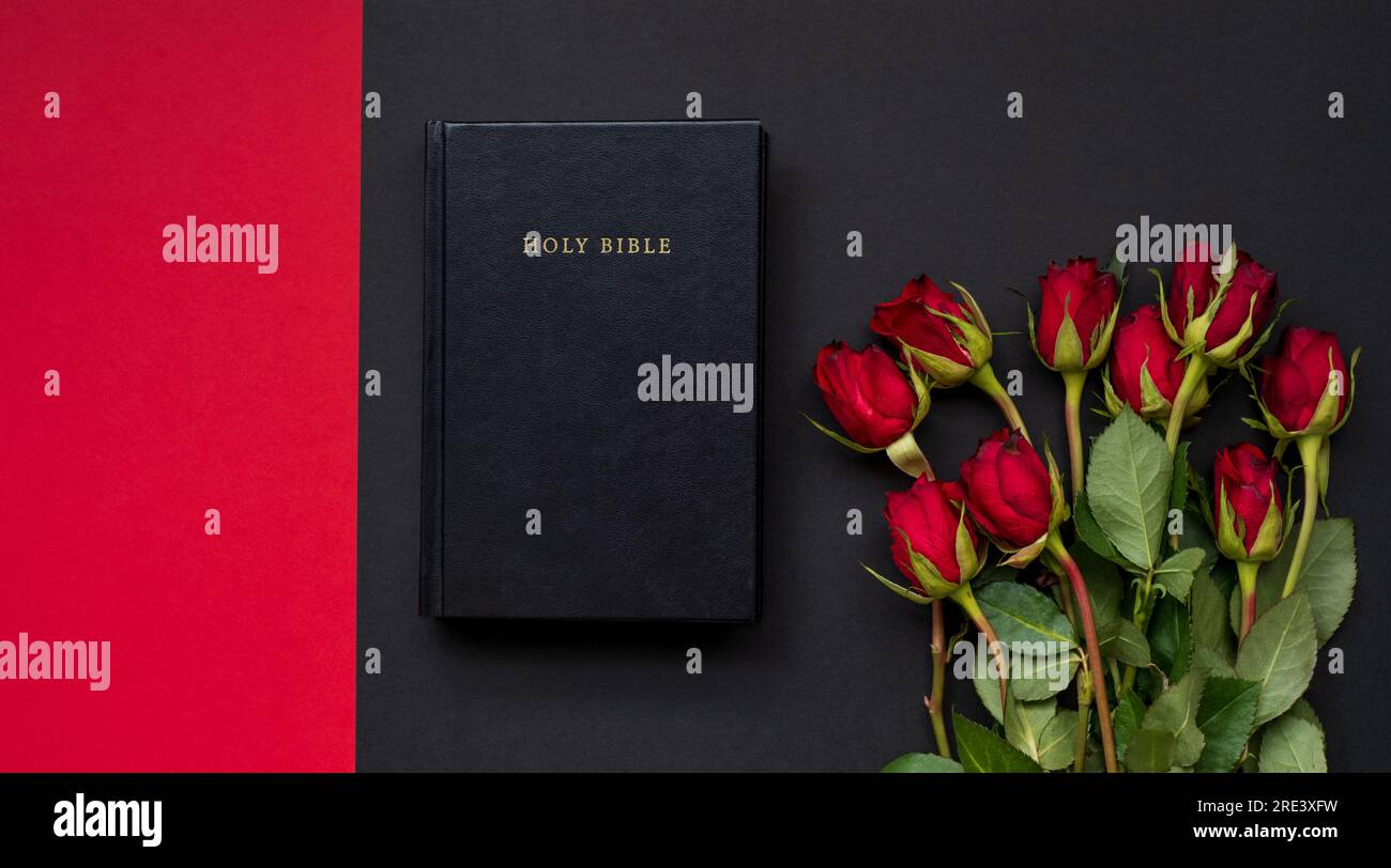 Heilige Bibel und rote Rosen auf schwarzem und rotem Hintergrund ...