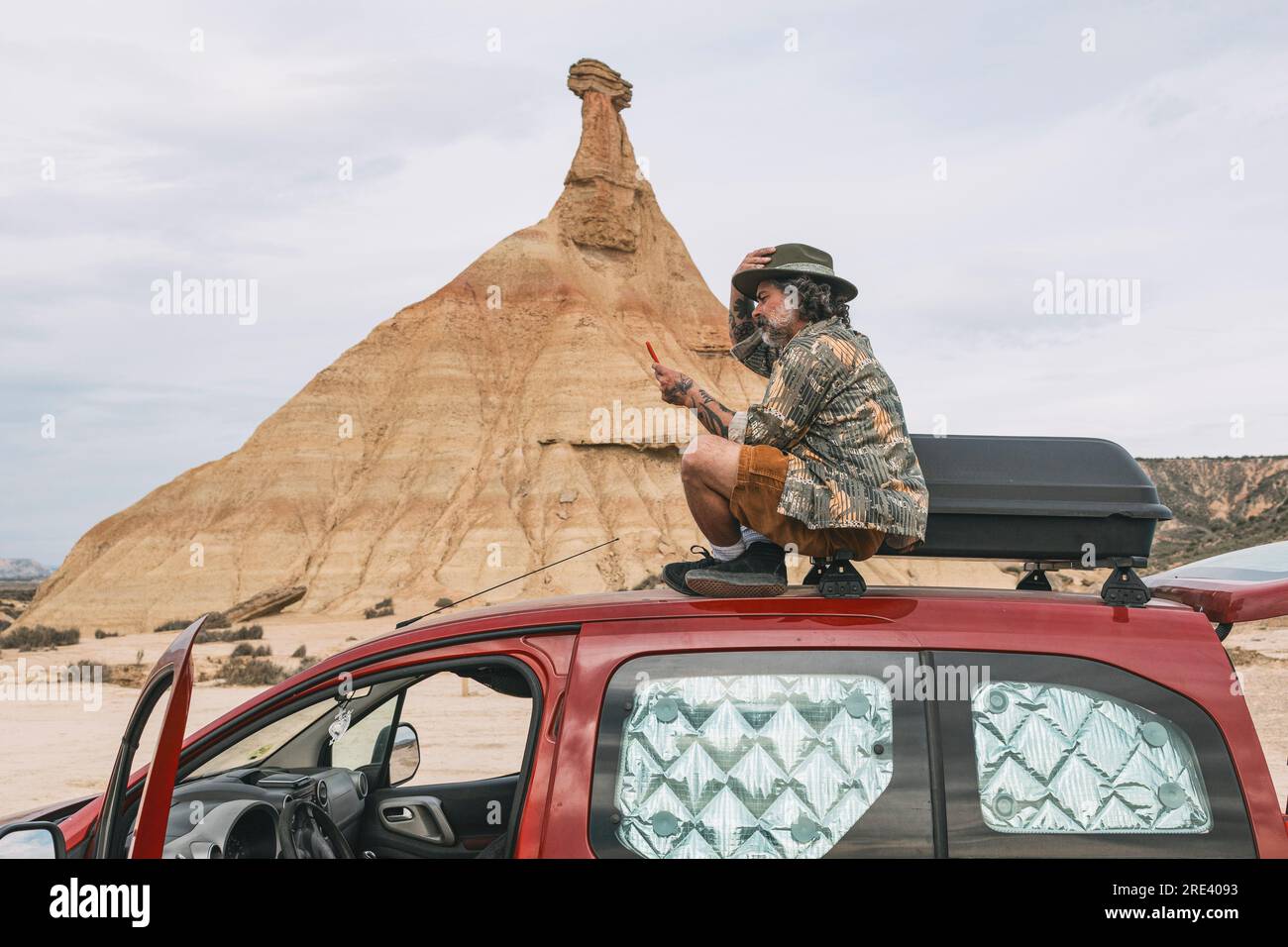 Ein Mann, der auf ein Handy in der Wüstenlandschaft von Bardenas Reales, Arguedas, Navarra, Spanien schaut Stockfoto