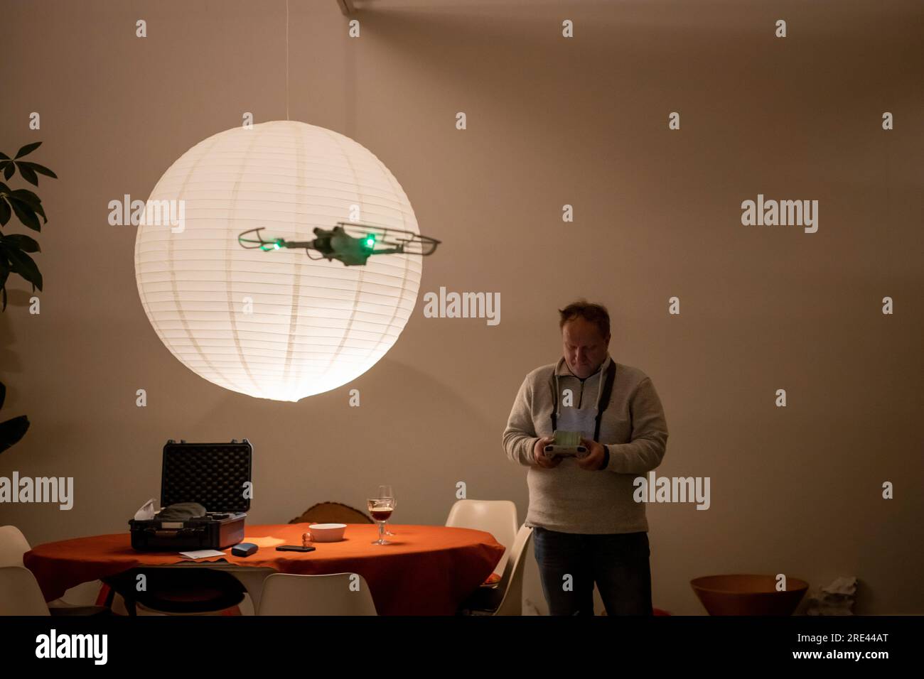 Ein Mann mittleren Alters, der drinnen eine Drohne fliegt Stockfoto