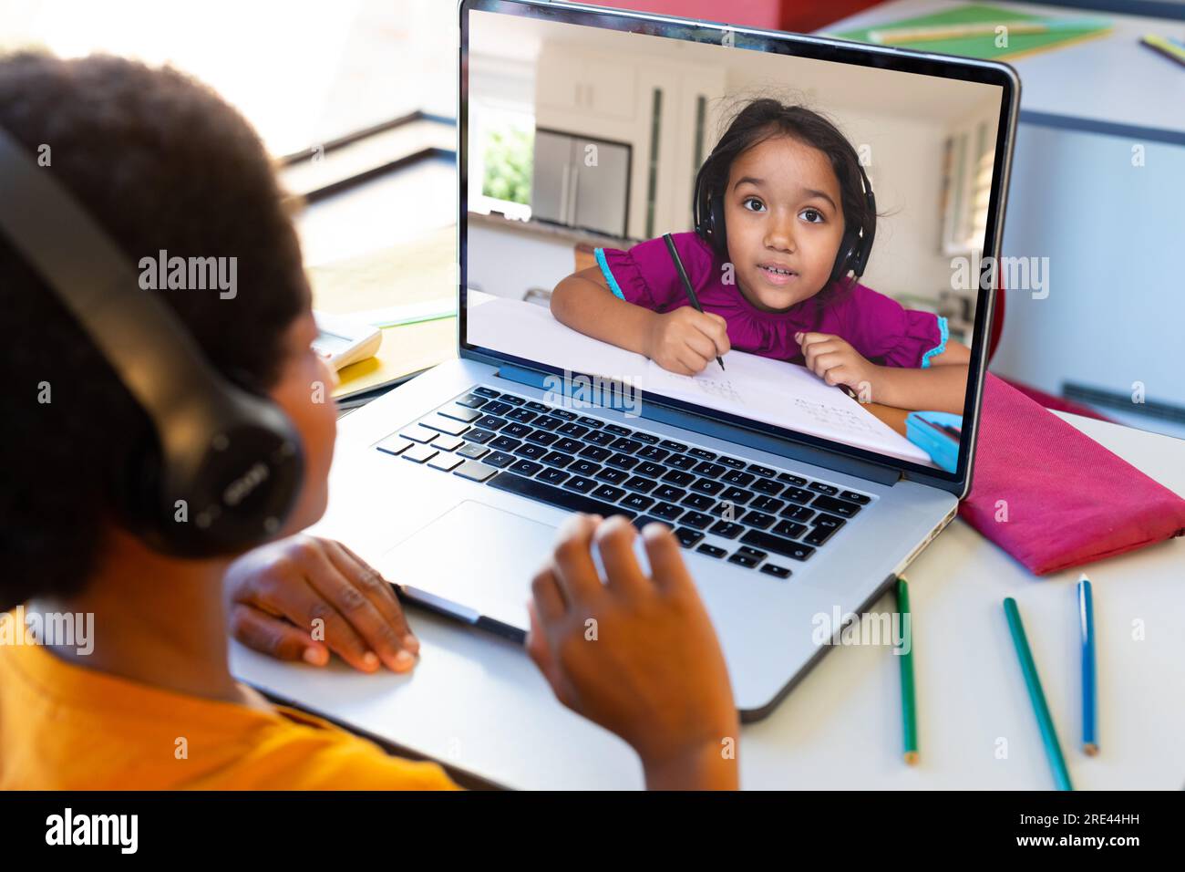 Ein birassistischer Junge mit Kopfhörern, der während des Online-Kurses auf dem Laptop-Bildschirm einen Freund ansieht Stockfoto