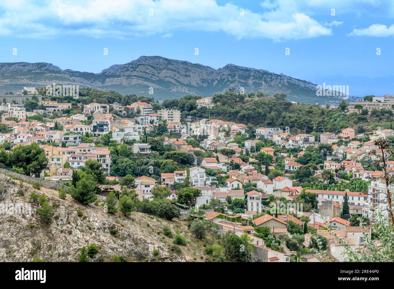 Stadtbild über Marseille, aufgenommen von der Basilika Notre-Dame von La Garde, mit Blick auf Terrakotta-Dächer, verwinkelte Straßen und entfernte Berge. Stockfoto