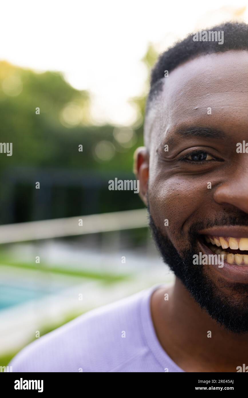 Ein halbes Porträt eines glücklichen afroamerikanischen Mannes auf der sonnigen Terrasse zu Hause mit Kopierraum Stockfoto