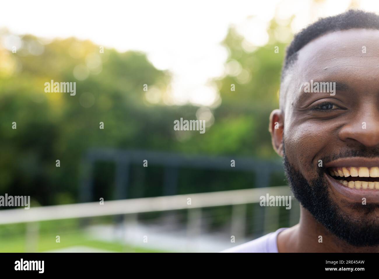 Ein halbes Porträt eines glücklichen afroamerikanischen Mannes auf der sonnigen Terrasse zu Hause mit Kopierraum Stockfoto
