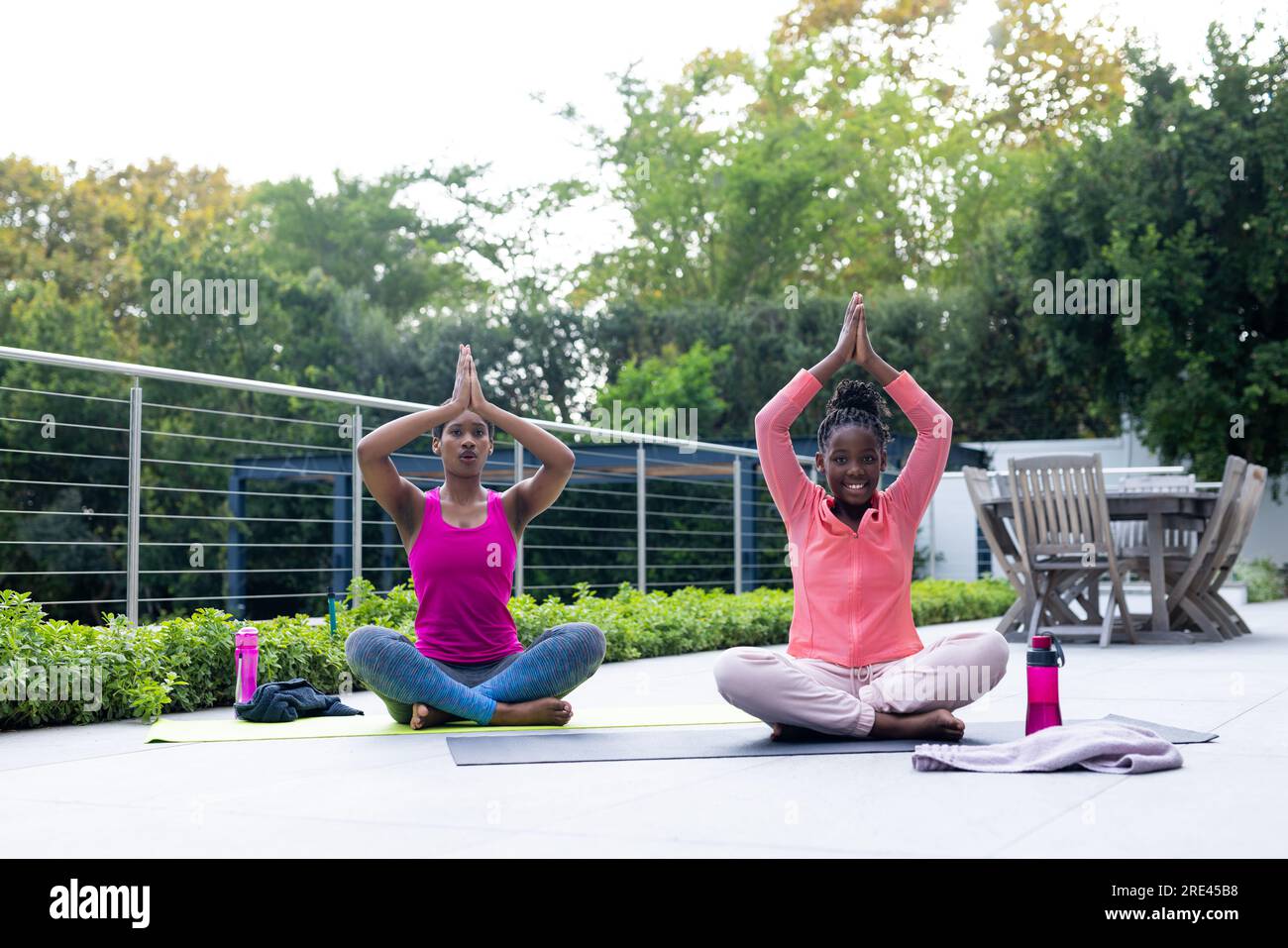 afroamerikanische Mutter und Tochter, die zu Hause Yoga auf der sonnigen Terrasse üben Stockfoto