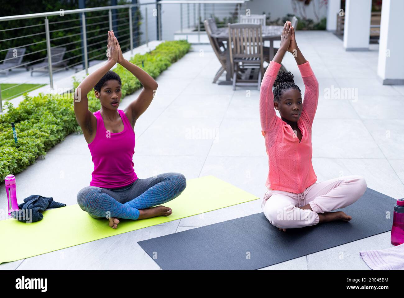 afroamerikanische Mutter und Tochter, die zu Hause Yoga auf der sonnigen Terrasse üben Stockfoto