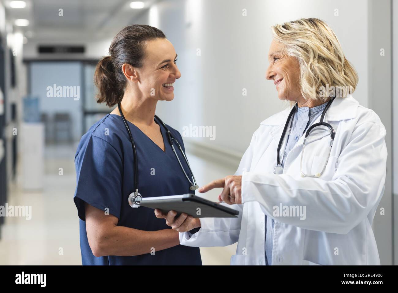 Glückliche weisse Ärztinnen mit Stethoskopen, die Tabletten im Krankenhaus benutzen Stockfoto