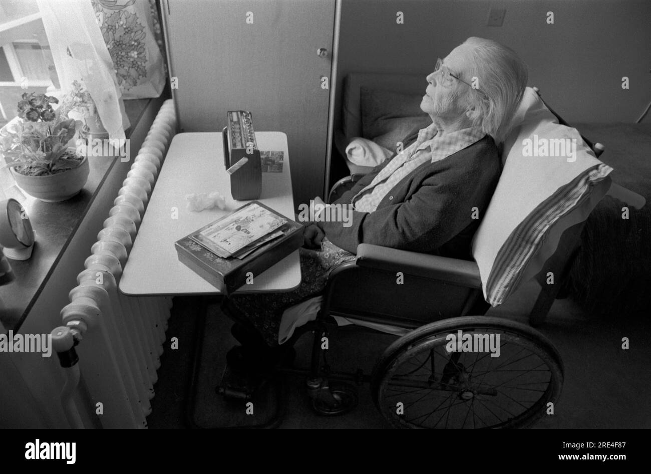 Altenpflegeheim 1970er Jahre Behinderte Frau allein im Rollstuhl und hört ihr tragbares Funkgerät. Erinnerungen vielleicht an die Vergangenheit. 70er Jahre England 1972 UK HOMER SYKES Stockfoto