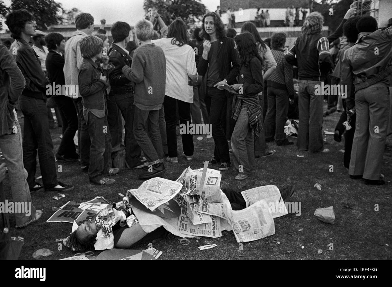 Erschöpfter Demonstrant, verpasst das Konzert, er schläft schnell. Er wurde von alten Zeitungen im Brockwell Park bei einem Rock Against Rassismus Konzert vertuscht. Sie marschierten 1978 vom Hyde Park London nach Brockwell Park nahe Brixton South London. HOMER SYKES AUS DEN 1970ER JAHREN. Stockfoto