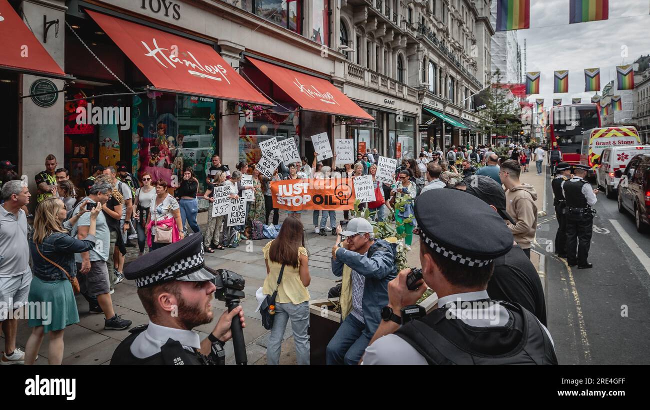 Die Polizei beobachtet Just Stop Oil, wenn sie vor dem Hamleys Spielzeugladen in London protestieren. Stockfoto