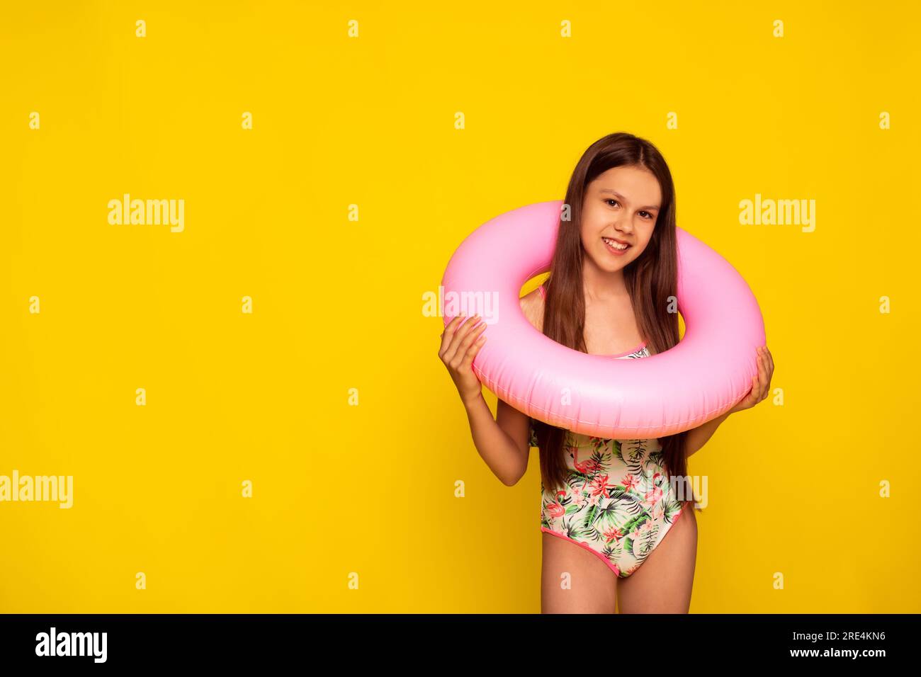 Teenager, die im Schwimmbad schwimmen lernen möchte, mit aufblasbarem Ring auf gelbem Hintergrund Stockfoto