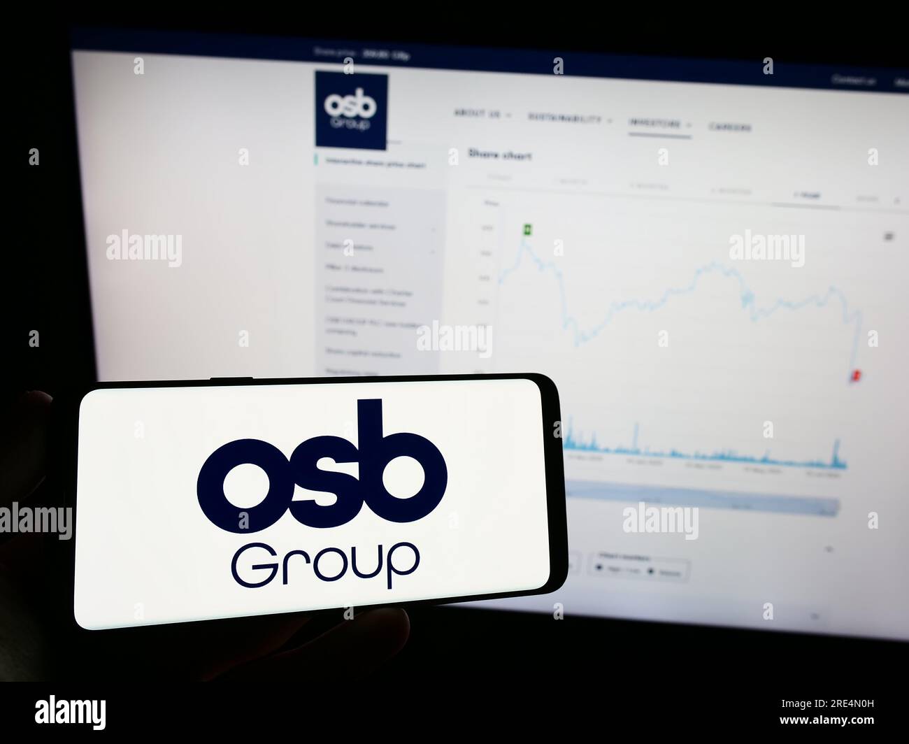 Person, die ein Mobiltelefon mit dem Logo des britischen Finanzunternehmens OSB Group plc auf dem Bildschirm vor der Unternehmenswebseite hält. Konzentrieren Sie sich auf das Display des Telefons. Stockfoto