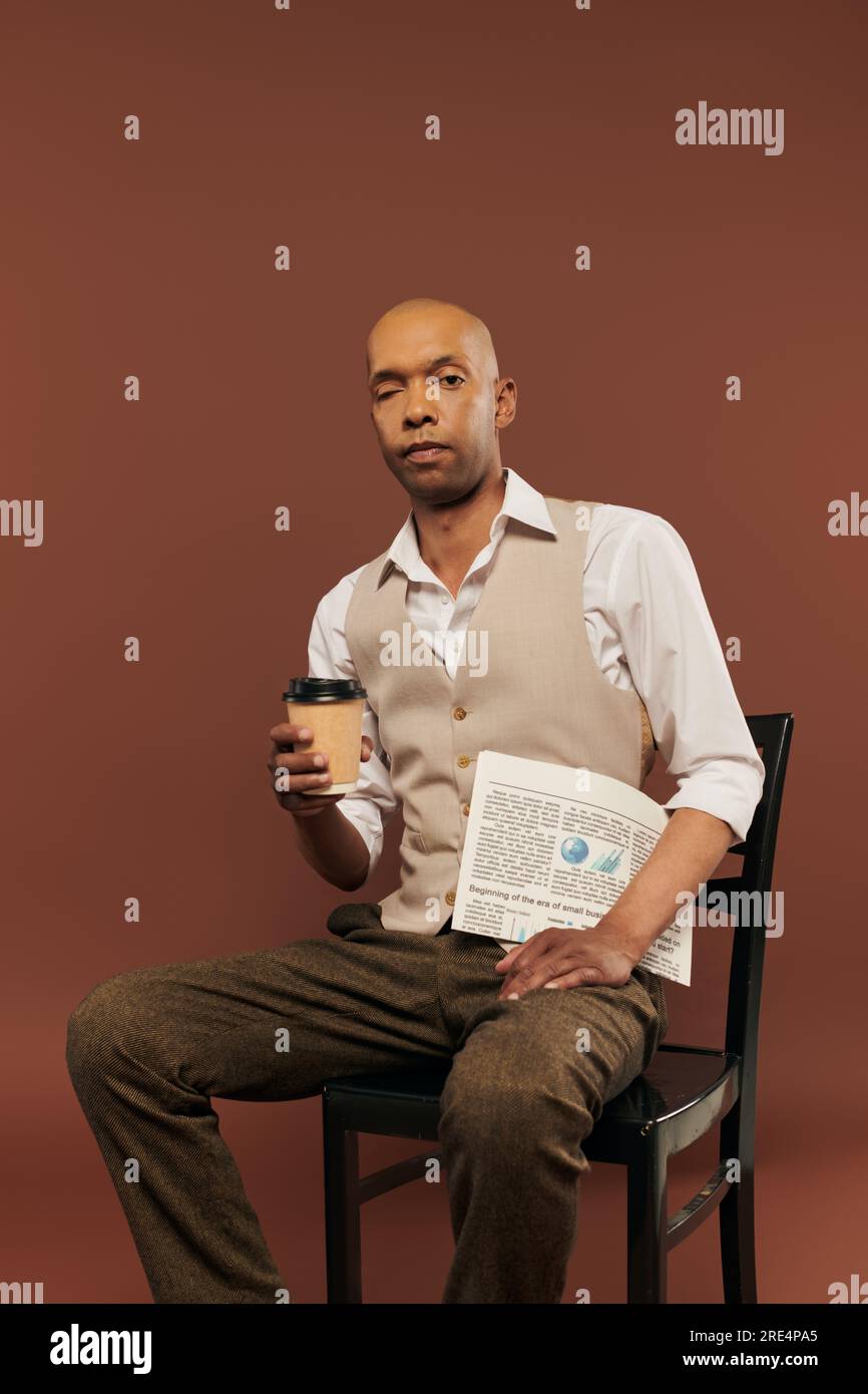 Inklusion, kühner afroamerikanischer Mann mit Myasthenia-gravis-Syndrom, sitzt auf einem Stuhl und hält einen Pappbecher mit Zeitung, Kaffee zum Mitnehmen, dunkle Haut Stockfoto