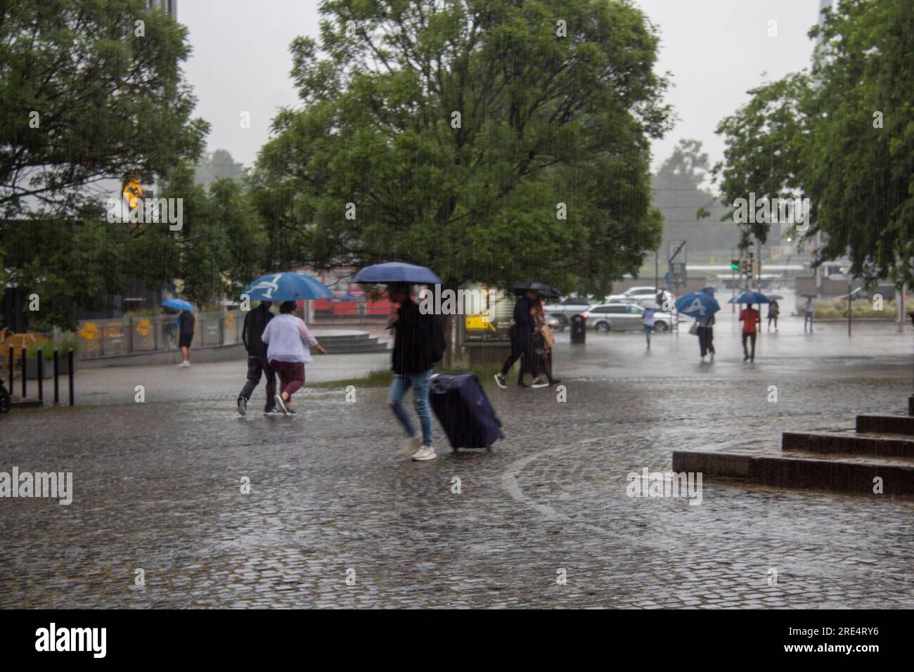 Leute, die bei Regen mit Sonnenschirmen in der Stadt spazieren gehen Stockfoto