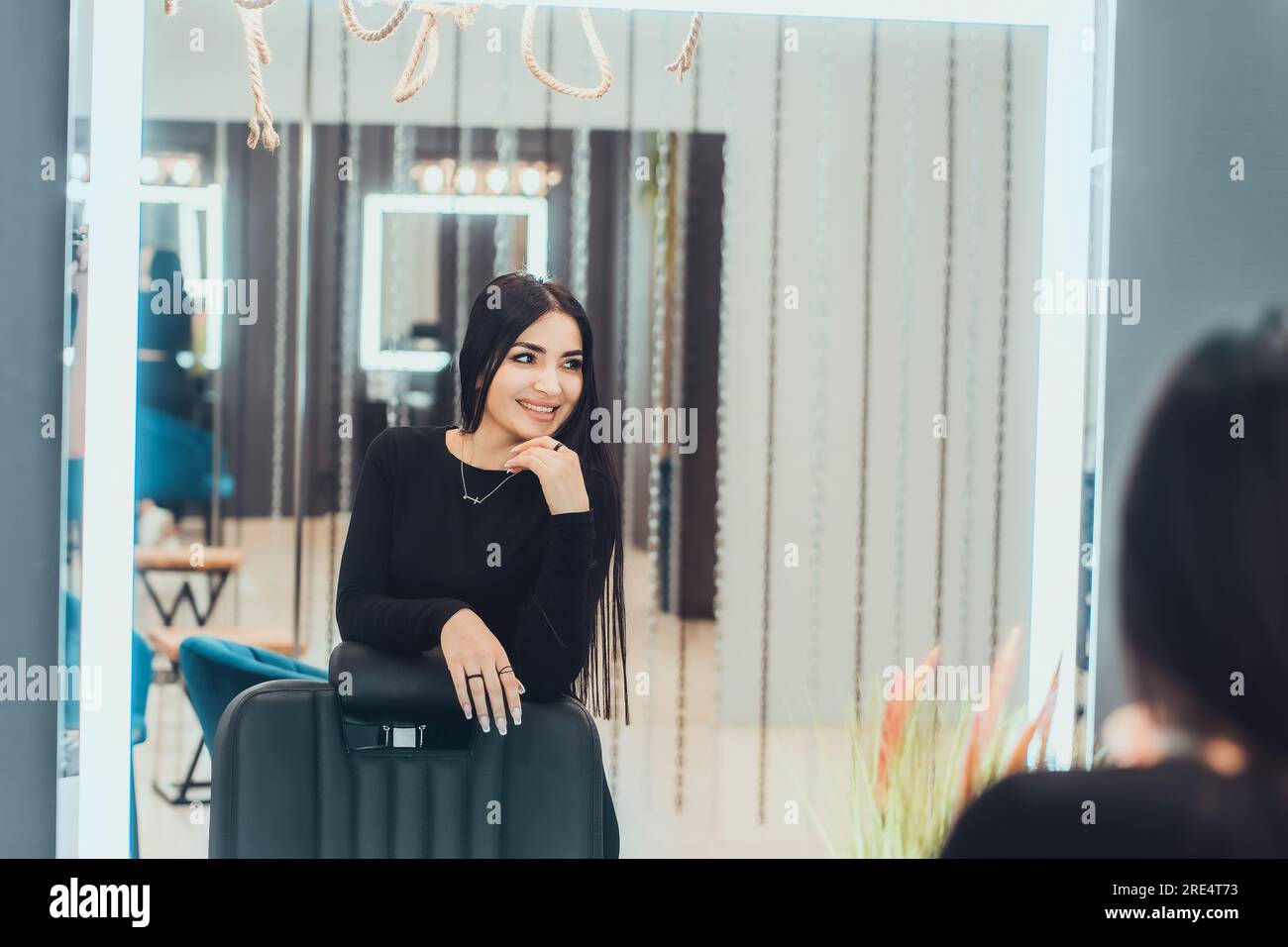 Porträt einer schönen Frau mit orientalischem Aussehen im Spiegel. Die schöne Brünette sieht in den Spiegel und lacht. Stockfoto