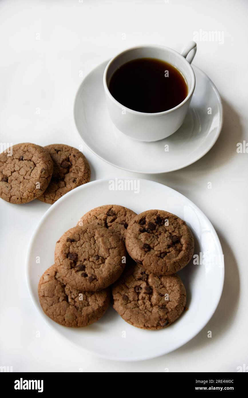Teepaar und Haferflocken-Kekse mit Schokolade auf weißem Hintergrund. Köstliches Mittagessen mit Tee und süßen Plätzchen. Porzellantee-Set mit einem heißen Getränk. Gute Güte Stockfoto