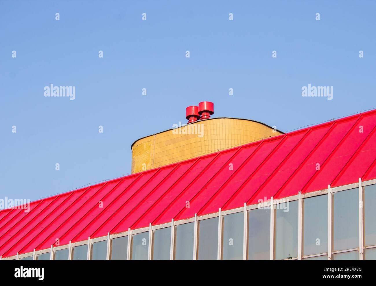 Rotes und gelbes Dach des Industriegebäudes mit blauem Himmel Stockfoto