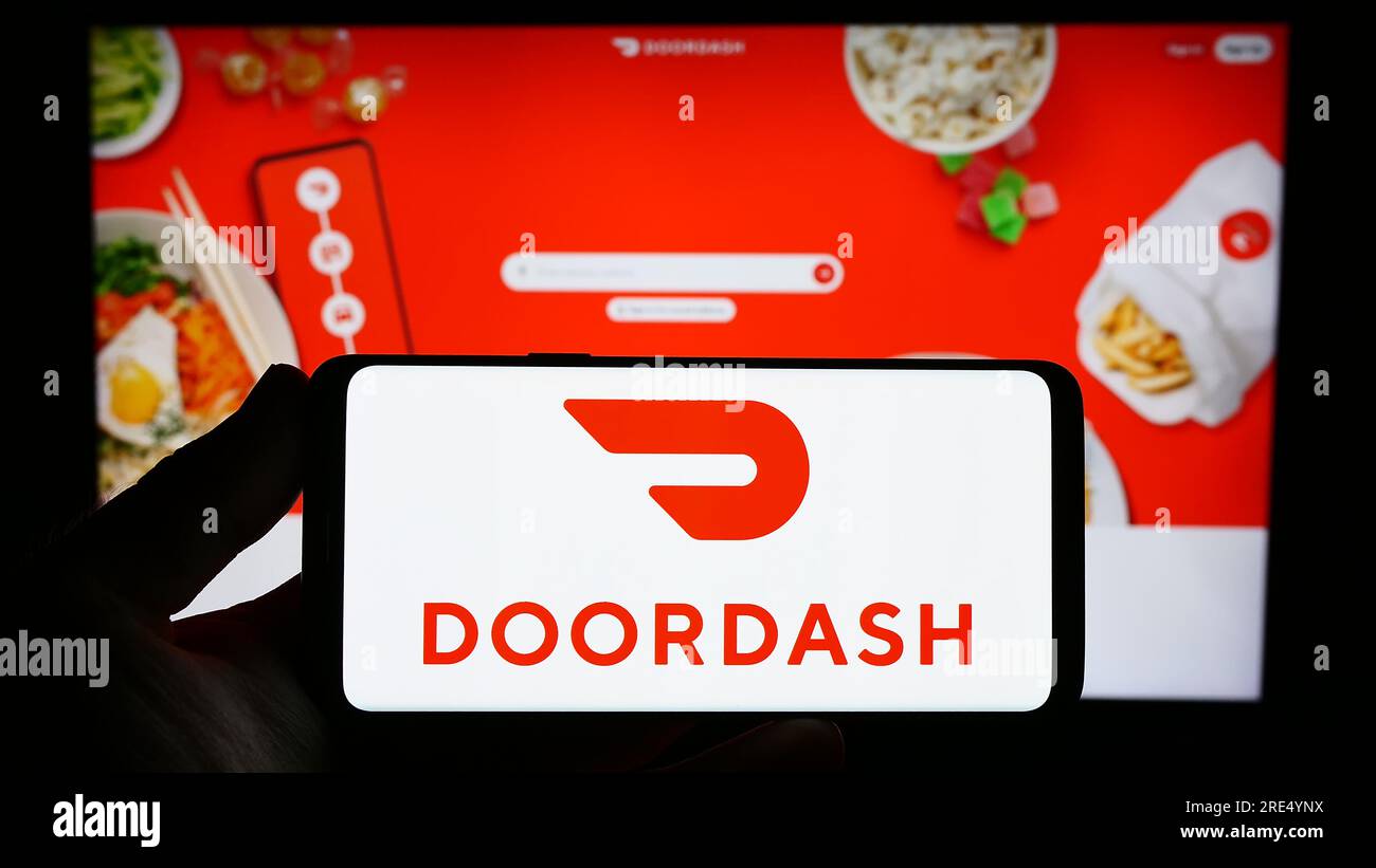 Person, die ein Smartphone mit dem Logo des US-amerikanischen Lieferunternehmens DoorDash Inc. Auf dem Bildschirm vor der Website hält. Konzentrieren Sie sich auf das Display des Telefons. Stockfoto