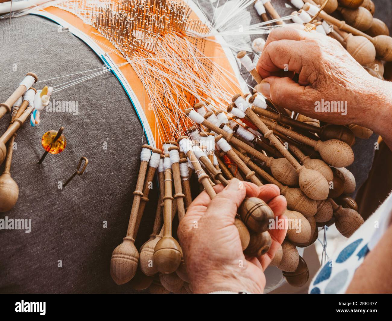 Hände einer Frau, die Spulenstickerei in einer Werkstatt weben. Lacemaker-Frau bei der Arbeit, traditionelles Schnürsenkel-Kunsthandwerk, Volkskunst, selektive Fokussierung Stockfoto