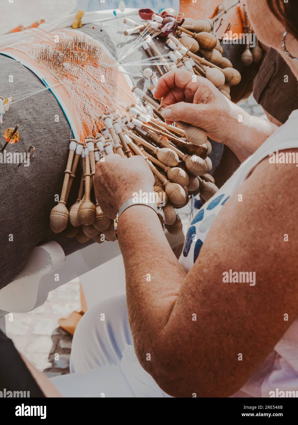 Hände einer Frau, die Spulenstickerei in einer Werkstatt weben. Lacemaker-Frau bei der Arbeit, traditionelles Schnürsenkel-Kunsthandwerk, Volkskunst, selektive Fokussierung Stockfoto