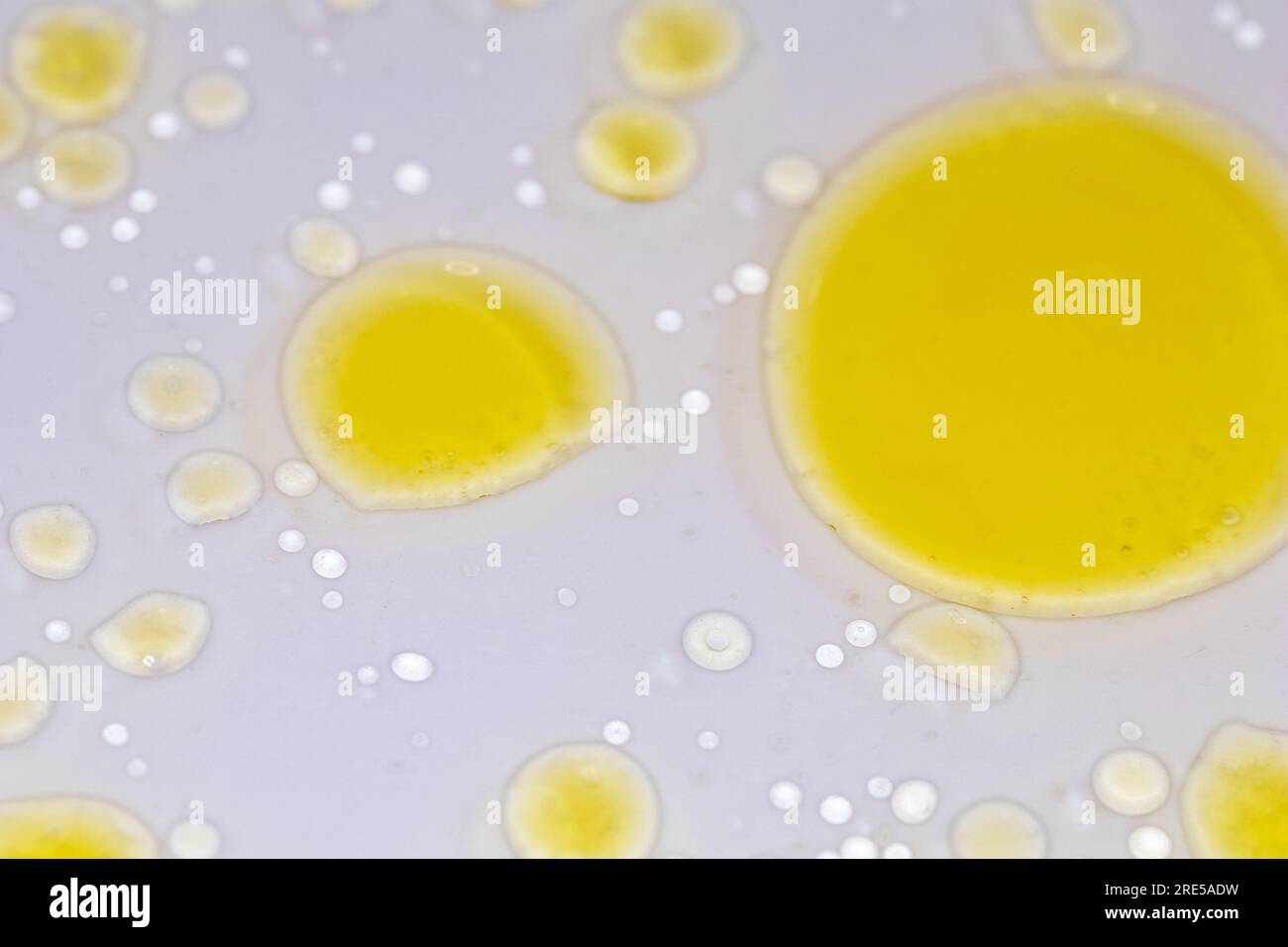 Gelbe Flüssigblasen auf weißem Hintergrund, abstrakter chemischer wissenschaftlicher Hintergrund Stockfoto