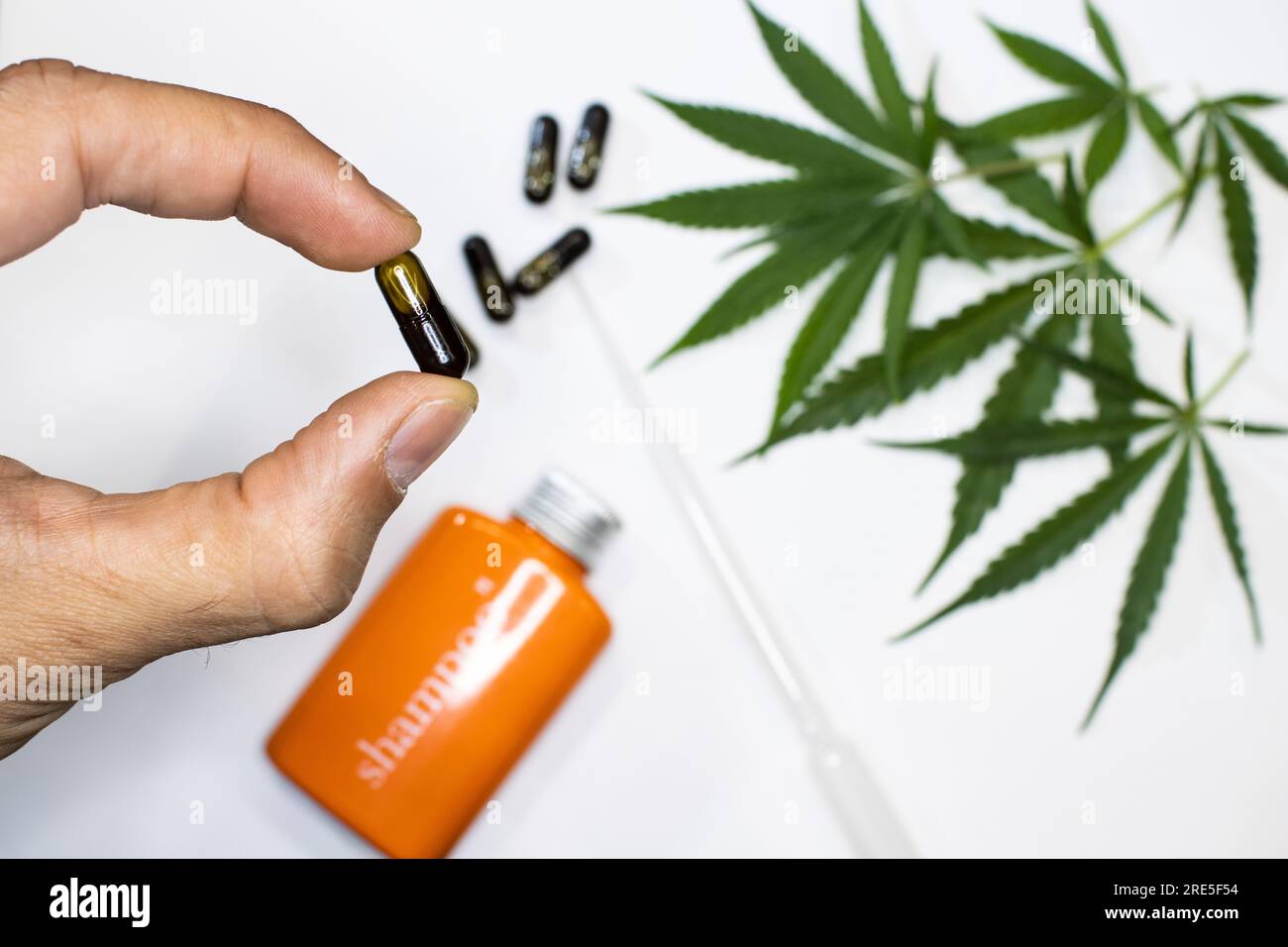 Hanfkosmetik mit Cannabisblättern im Hintergrund. CBD-Ölcreme und Pillen. Kosmetik-Marihuana-Konzept auf reinweißem minimalen Hintergrund Stockfoto