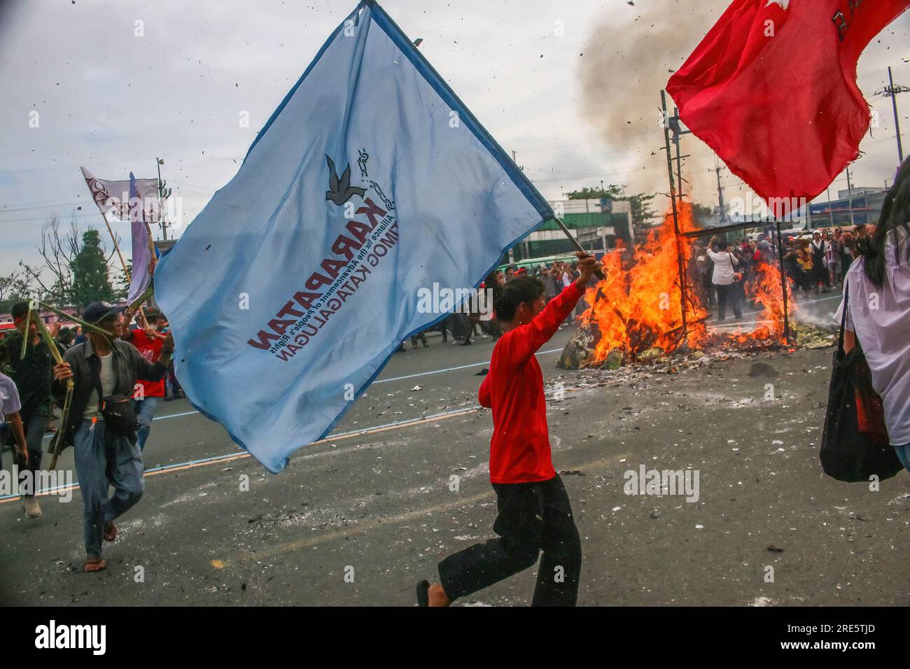 Quezon, Philippinen. 24. Juli 2023. Demonstranten mit Flaggen gehen vor seiner zweiten Rede zur Lage der Nation am brennenden Bildnis von Präsident Ferdinand Marcos Jr. vorbei. Die Demonstranten konzentrierten sich auf die Menschenrechtsverletzungen der Regierung, die souveränen Rechte über der Westphilippinischen See, Arbeitslosigkeit, Lohnerhöhungen und andere soziale Probleme, mit denen das Land noch immer konfrontiert ist. Kredit: SOPA Images Limited/Alamy Live News Stockfoto