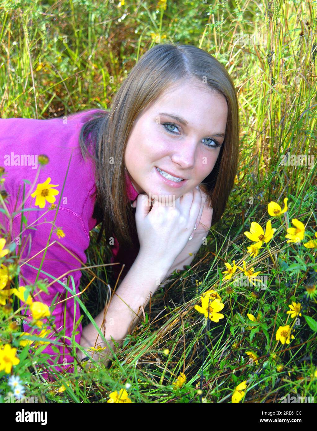 Auf einer Wiese voller Wildblumen lacht die junge Frau und genießt es, am frühen Morgen mit der Natur zu kommunizieren. Stockfoto