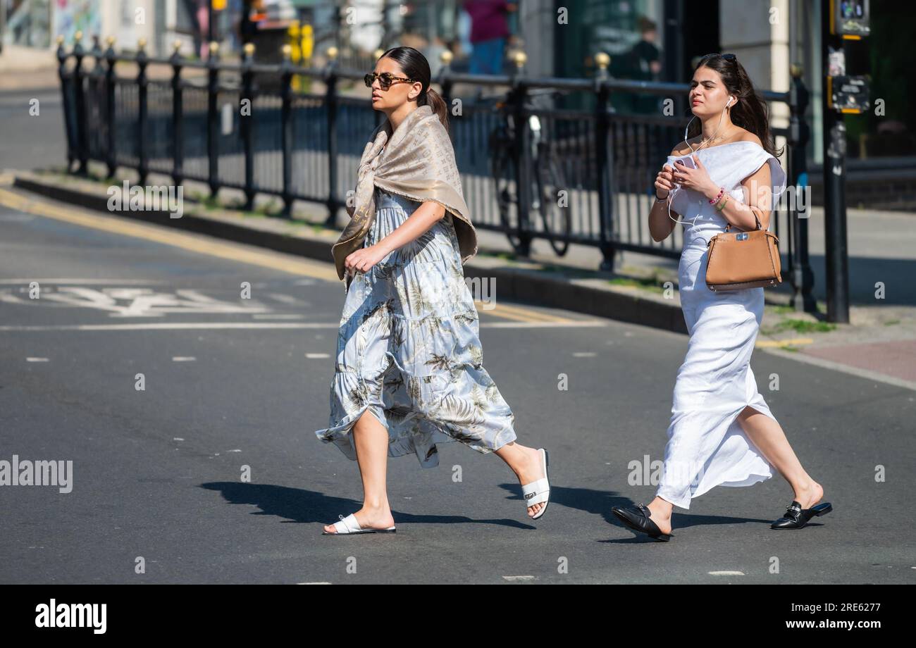 Zwei junge Frauen, die im Sommer eine belebte Straße überqueren könnten, sehen gut gekleidet, elegant, selbstbewusst und stilvoll aus. In Brighton & Hove, England, Großbritannien. Stockfoto