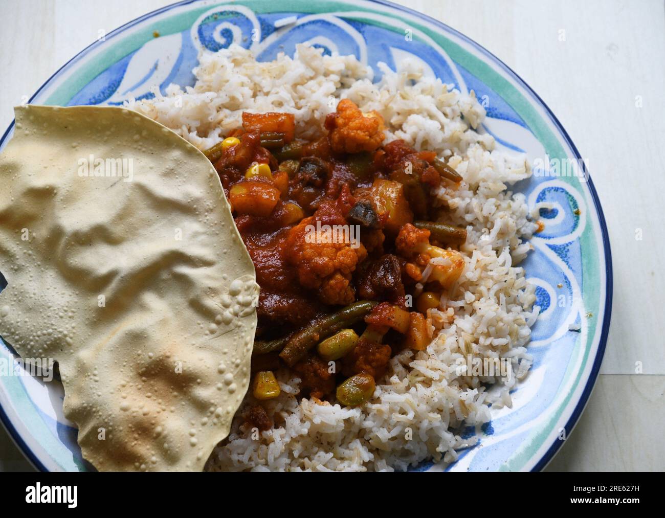 Ein einfaches Gemüse-Curry mit Pilzen, Blumenkohl, Apfel, Sultaninen und gemischtem Gemüse. Ein Popadom und Reis vervollständigen die einfache Vorbereitung Stockfoto