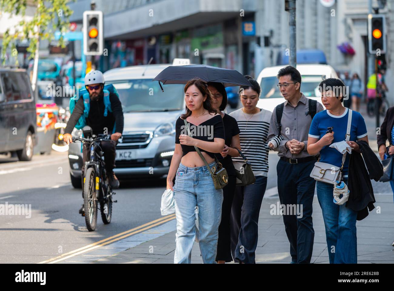 Gruppe von möglicherweise japanischen Touristen, die im Sommer auf einer geschäftigen Straße in Brighton & Hove, East Sussex, England, spazieren. Stockfoto