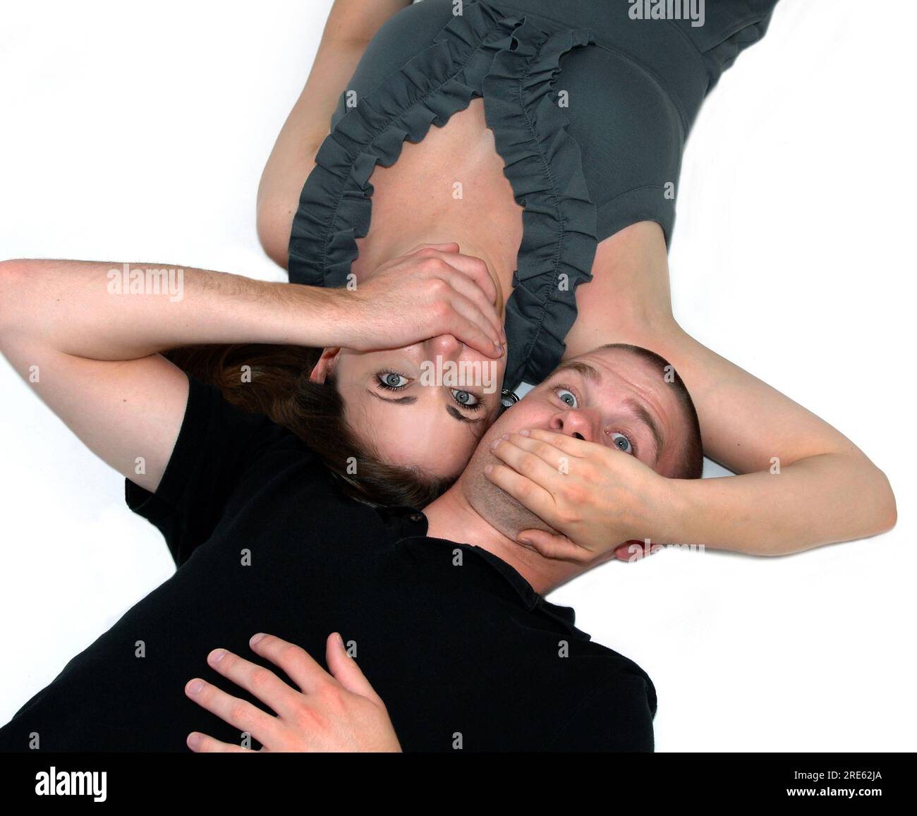 Mann und Frau lagen auf weißem Boden, gegenüberliegend. Jeder hat seine Hände über den Mund des anderen. Konzeptionelle Ideen könnten Geheimnisse sein. Stockfoto