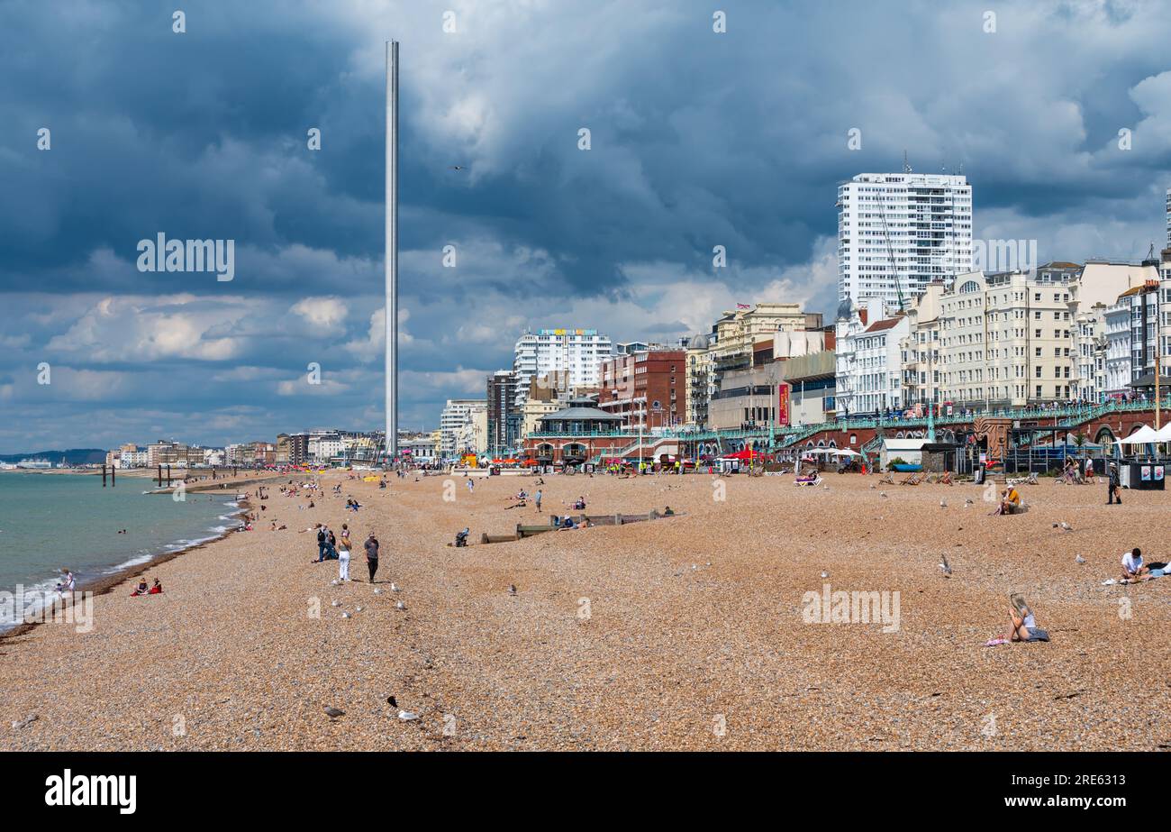 Menschen am Strand mit Blick nach Westen entlang der Küste, an einem bedeckten, wolkigen Sommertag im britischen Küstenort Brighton & Hove, Großbritannien. Stockfoto