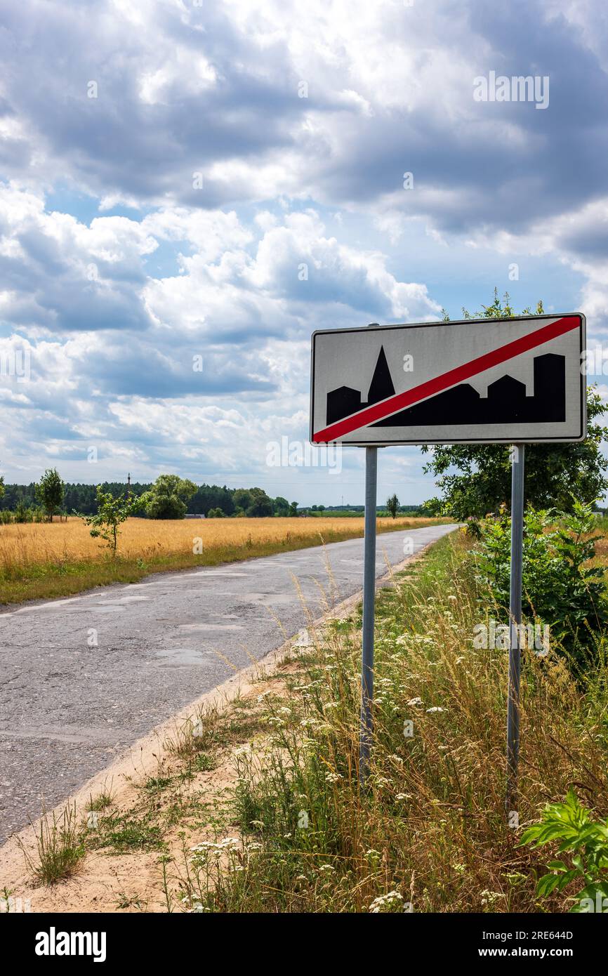 Straßenschild auf einer leeren Straße außerhalb eines polnischen Dorfes, ländliche Gemeinde, polnische Landschaft, Weizenfelder. Armut. Stockfoto