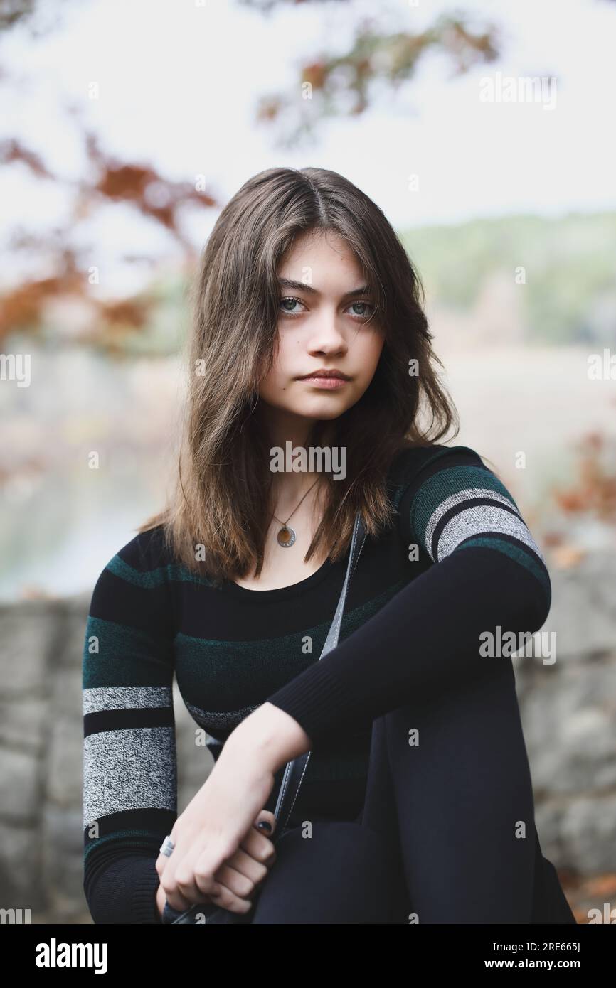 Wunderschöne braune junge Frau, die in die Kamera blickt und sich von Herbstfarben umgeben hat. Selektiver Fokus. Stockfoto