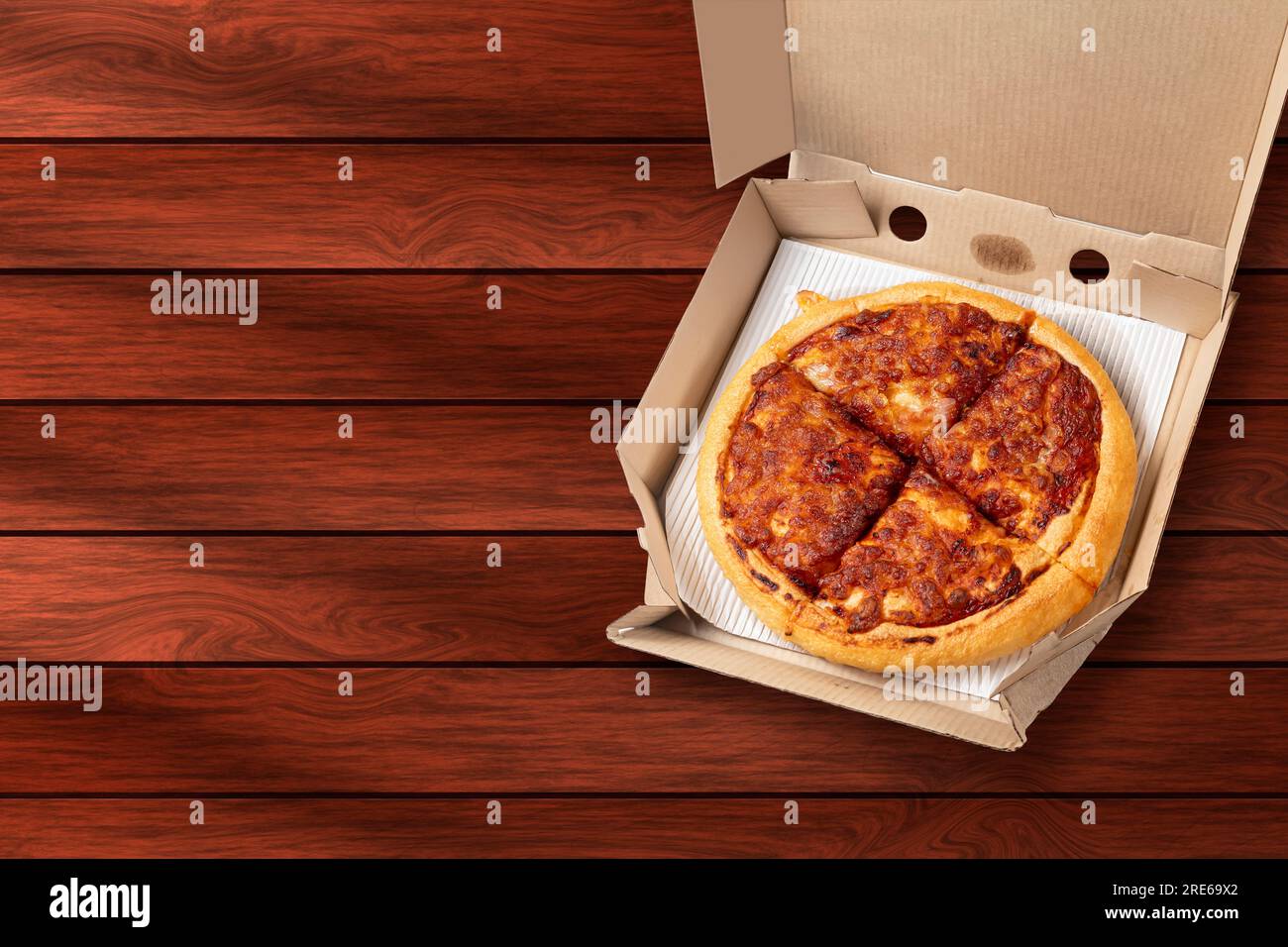 Margherita-Pizza in offener Lieferkarton auf Holzhintergrund. Stockfoto