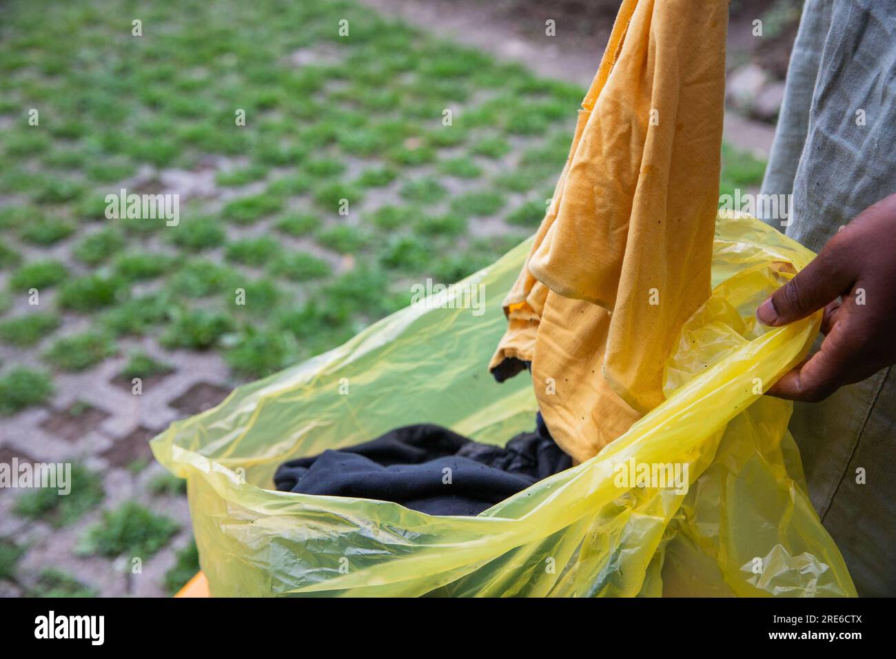 Eine Frau wirft gebrauchte Kleidung in einen Recyclingbeutel, Mülltrennung, um die Umwelt nicht zu verschmutzen. Stockfoto