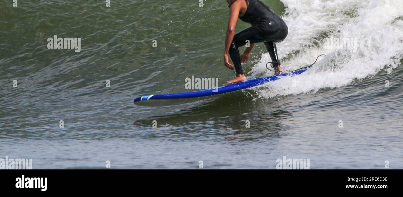 Seitenansicht eines surfenden Mannes in einem Neoprenanzug auf einer Welle vor der Küste von Long Island. Stockfoto