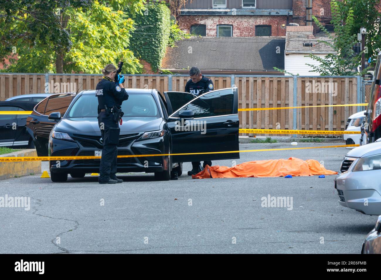 Toronto, Kanada, 25. Juli 2023. Die Polizei von Toronto untersucht eine tödliche Schießerei bei Tageslicht auf einem Parkplatz im Downtown East End der Stadt Die Polizei sagt, der Mord scheint das Ziel zu sein. Colin N. Perkel/Alamy Live News Stockfoto