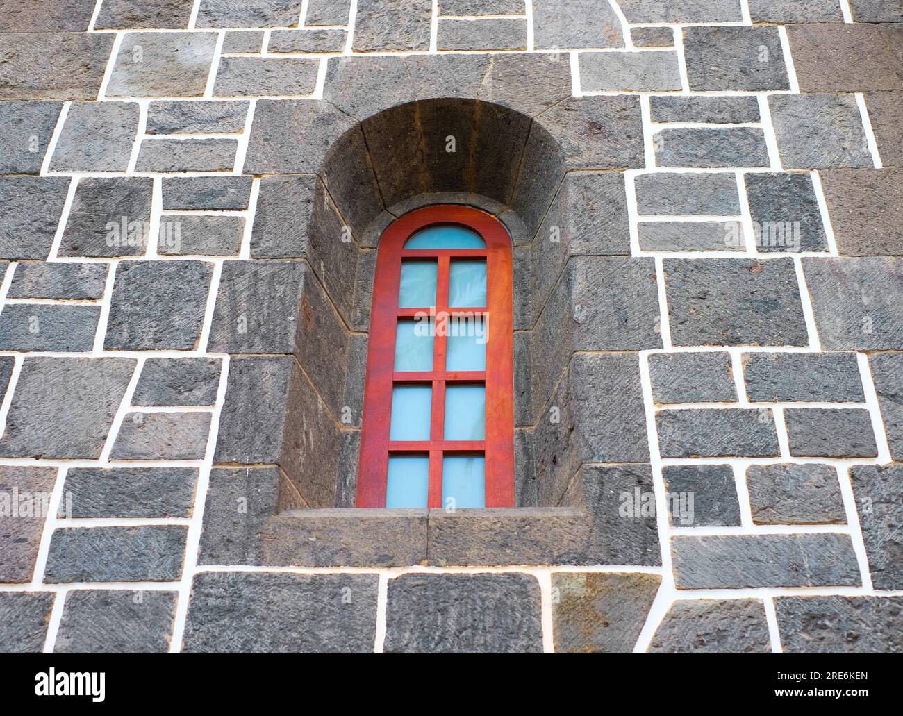 Kleines, hohes klassisches Fenster in einer alten Steinmauer. Stockfoto