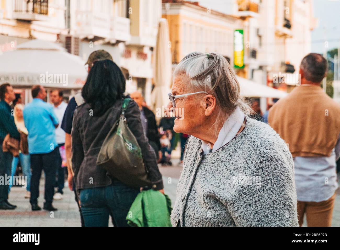 Eine ältere Frau mit Gehstock macht eine Pause in einer von Touristen gefüllten Hauptstraße in Plovdiv, Bulgarien Stockfoto